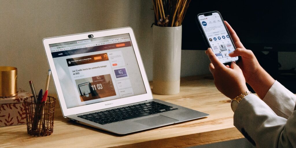 a person holding a phone and a laptop